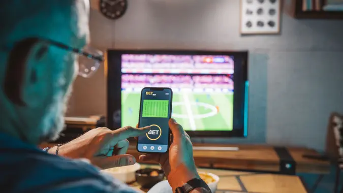 Mature men sitting on sofa at home and watching soccer game.