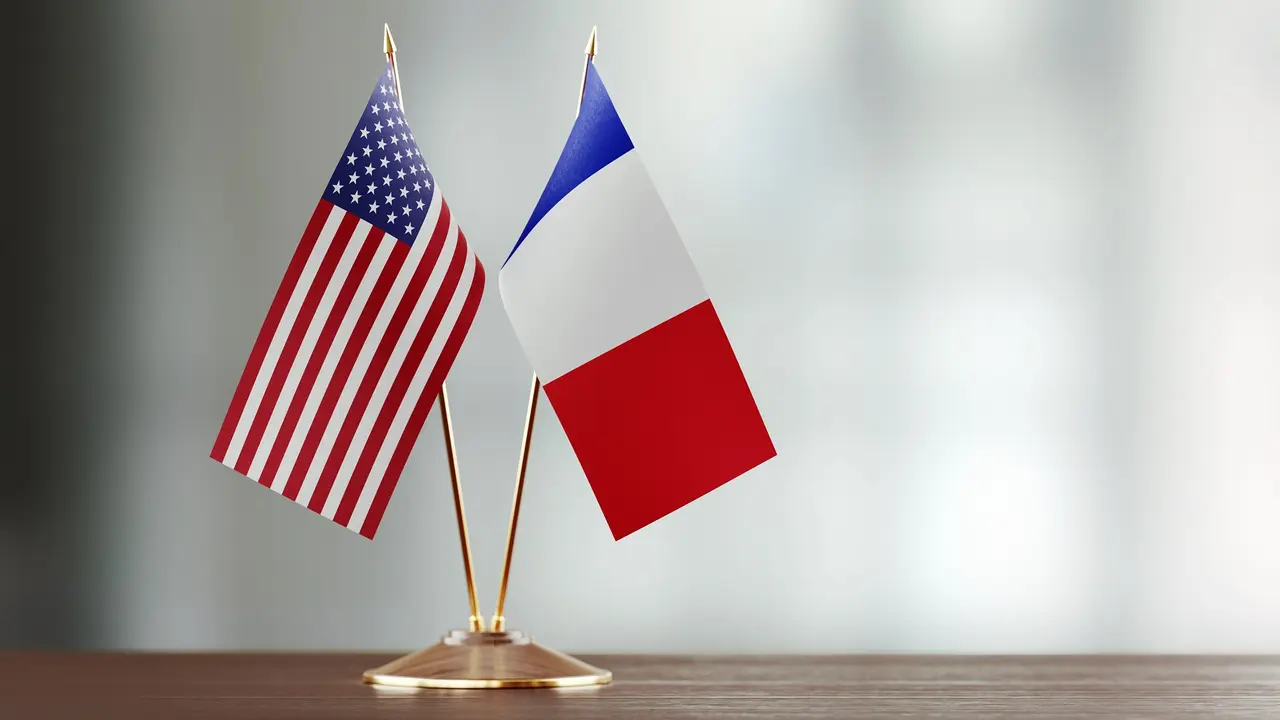 American And French Flag Pair On A Desk Over Defocused Background stock photo