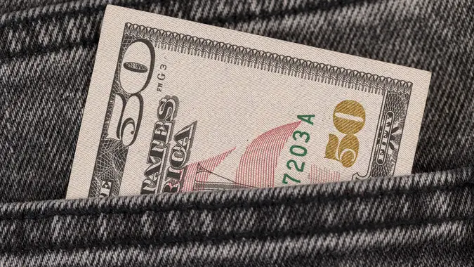 Fifty dollars are in the pocket of gray jeans stock photo