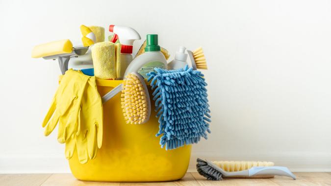 Brushes, bottles with cleaning liquids, sponges, rag and yellow rubber gloves on white background.