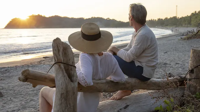 Mature couple relax by tropical beach at sunrise stock photo