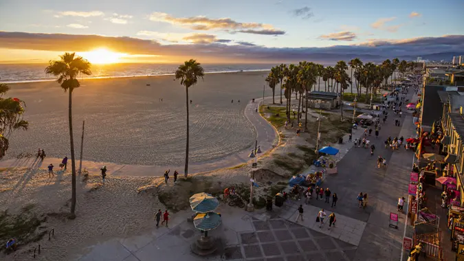 Tourists walking on footpath by beach during sunset stock photo