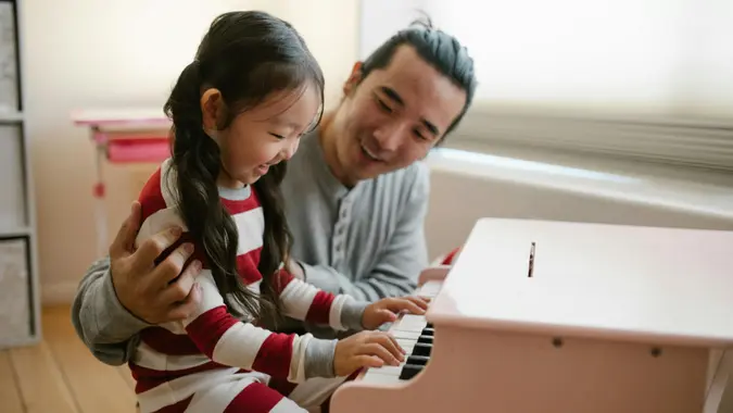 Father and daughter playing piano together in their home