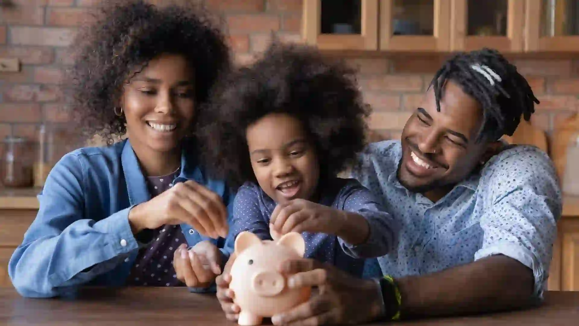 Caring young African American parents teaching small daughter saving money, stock photo