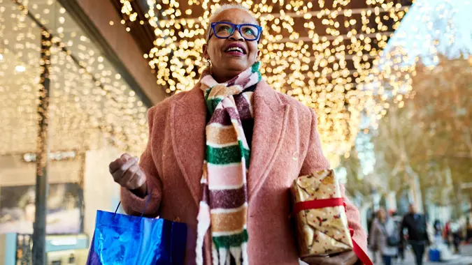 Smiling Christmas shopper carrying bag and gift stock photo