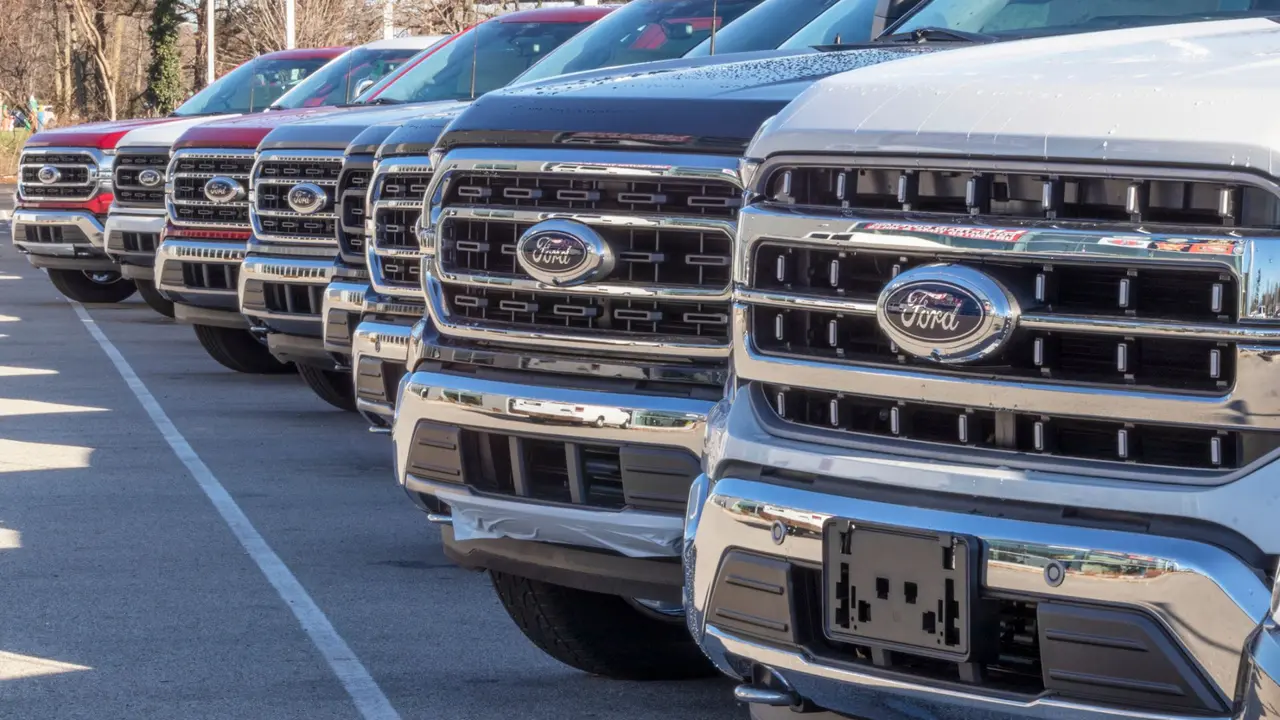 A lineup of Ford cars on a dealership lot, zoomed in to focus on the Ford logo