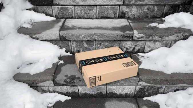Toronto, ON, Canada - January 27, 2023: A flat Amazon shipping box delivered at doorstep with snow on the sides.