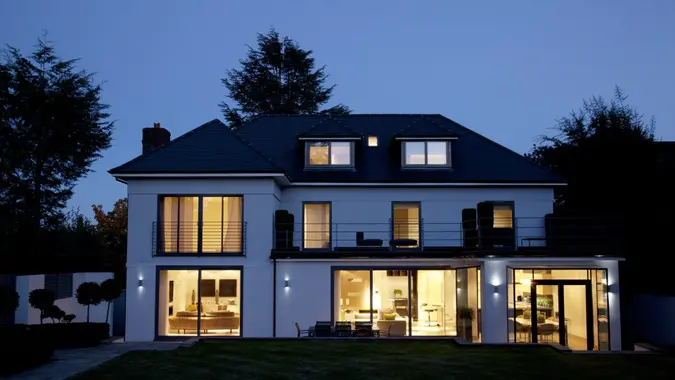 An upscale modern house illuminated at night to showcase haunted histories or spooky real estate tales.
