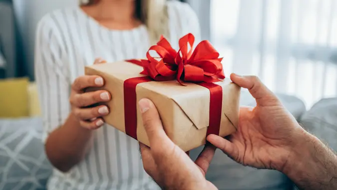 Cheerful young woman receiving a gift from her boyfriend. stock photo