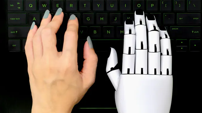 Robot concept chatbot of Human hand and robot hand pressing computer keyboard enter stock photo