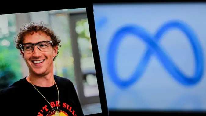 In this photo illustration, a person is holding a mobile phone with MARK ZUCKERBERG facebook account with Meta Logo in the background.