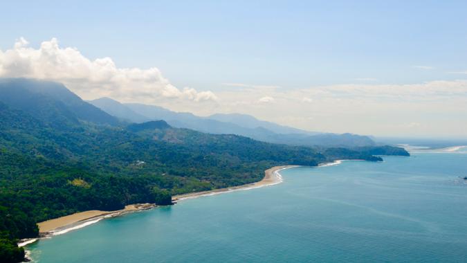 Vibrant tropical forests flow down from the mountains to the sandy beaches along the coast.