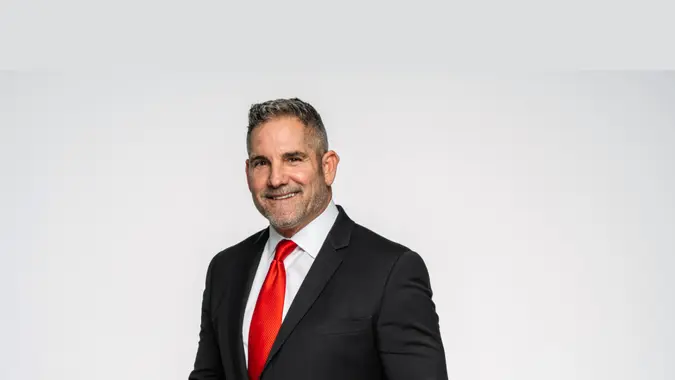 Grant Cardone smiling in a suit with a red tie