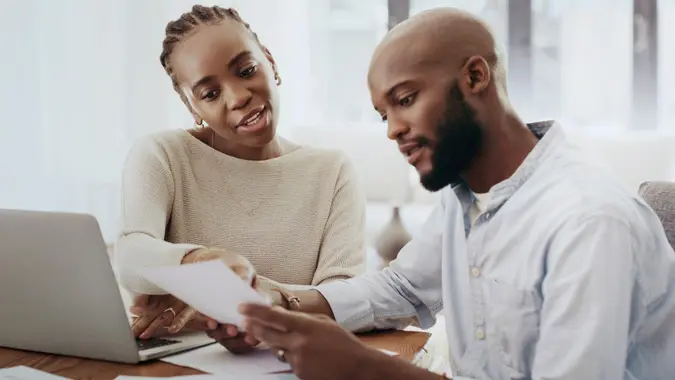 A couple with a laptop reviewing papers together in their home.