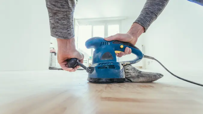 Close up of a sander power tool for DIY on wooden parquet floor.