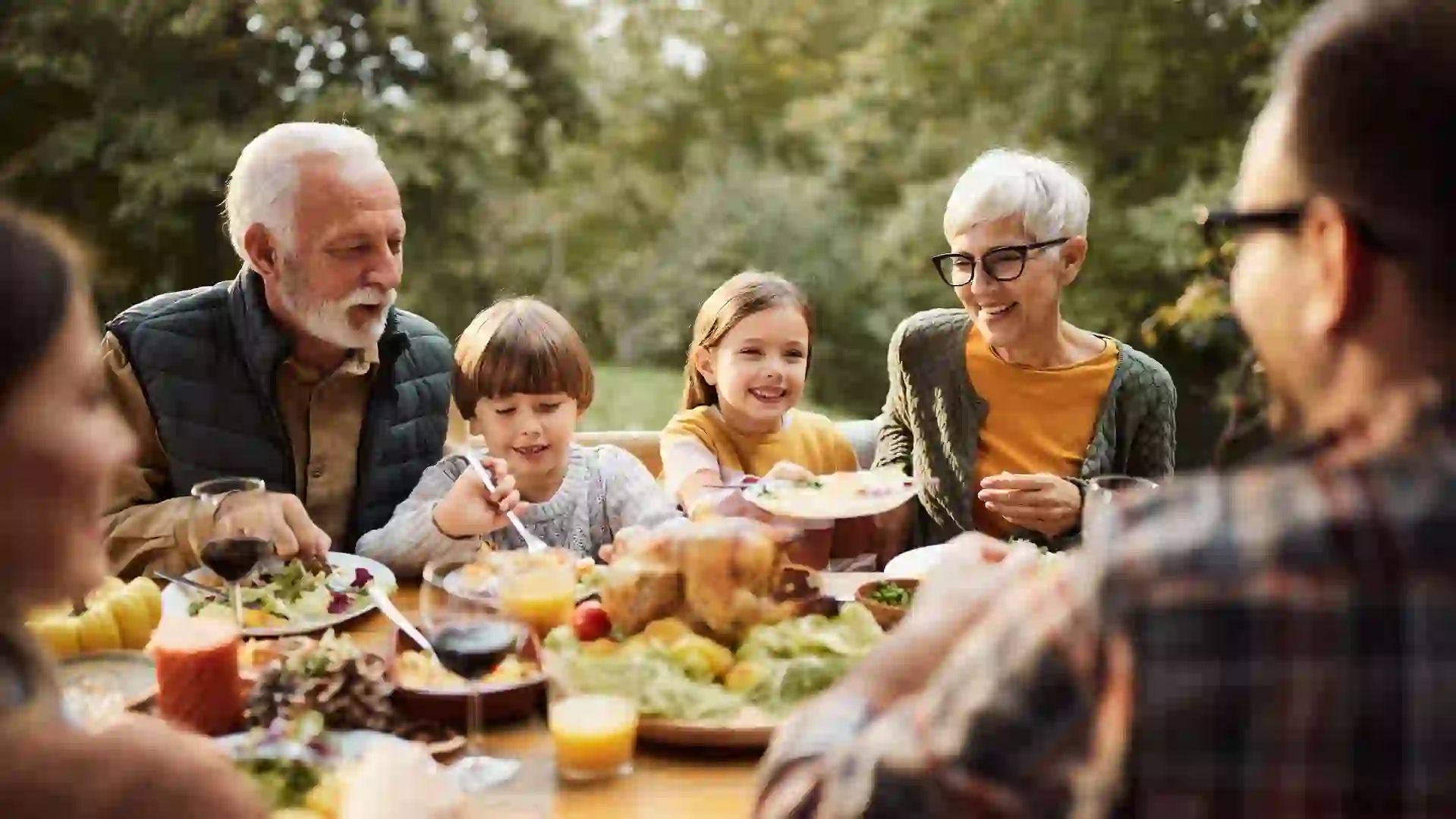 Happy extended family talking during a meal in nature.