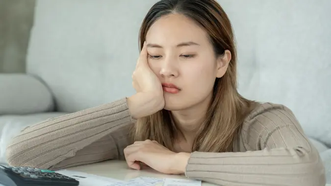 Stressed and headache asian woman with large bills or invoices no money to pay to expenses and credit card debt. shortage, Financial problems, mortgage, loan, bankruptcy, bankrupt, poor, empty wallet stock photo