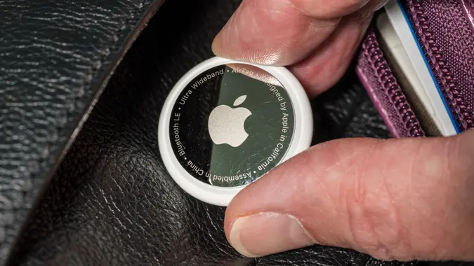 Apple AirTag being inserted into a leather purse stock photo