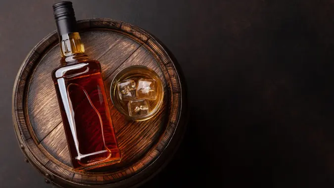 Scotch whiskey bottle, glass and old wooden barrel.