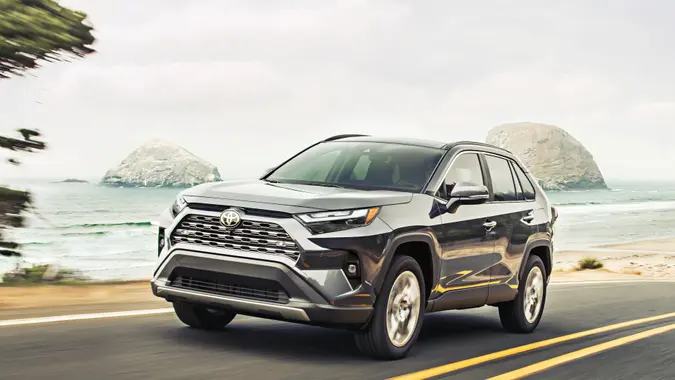 Toyota RAV4 driving down the road with a beach in the background.
