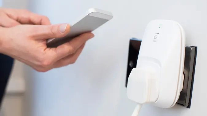 Woman Controlling Smart Plug Using App On Mobile Phone stock photo