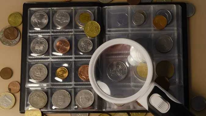 Working with a collection of coins on the table magnifying glass stock photo