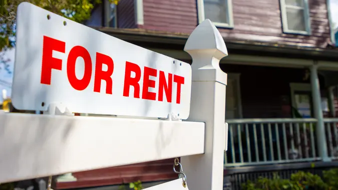A red and white for rent sign in front of a house