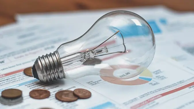 Detail of electricity bills with light bulb and coins.