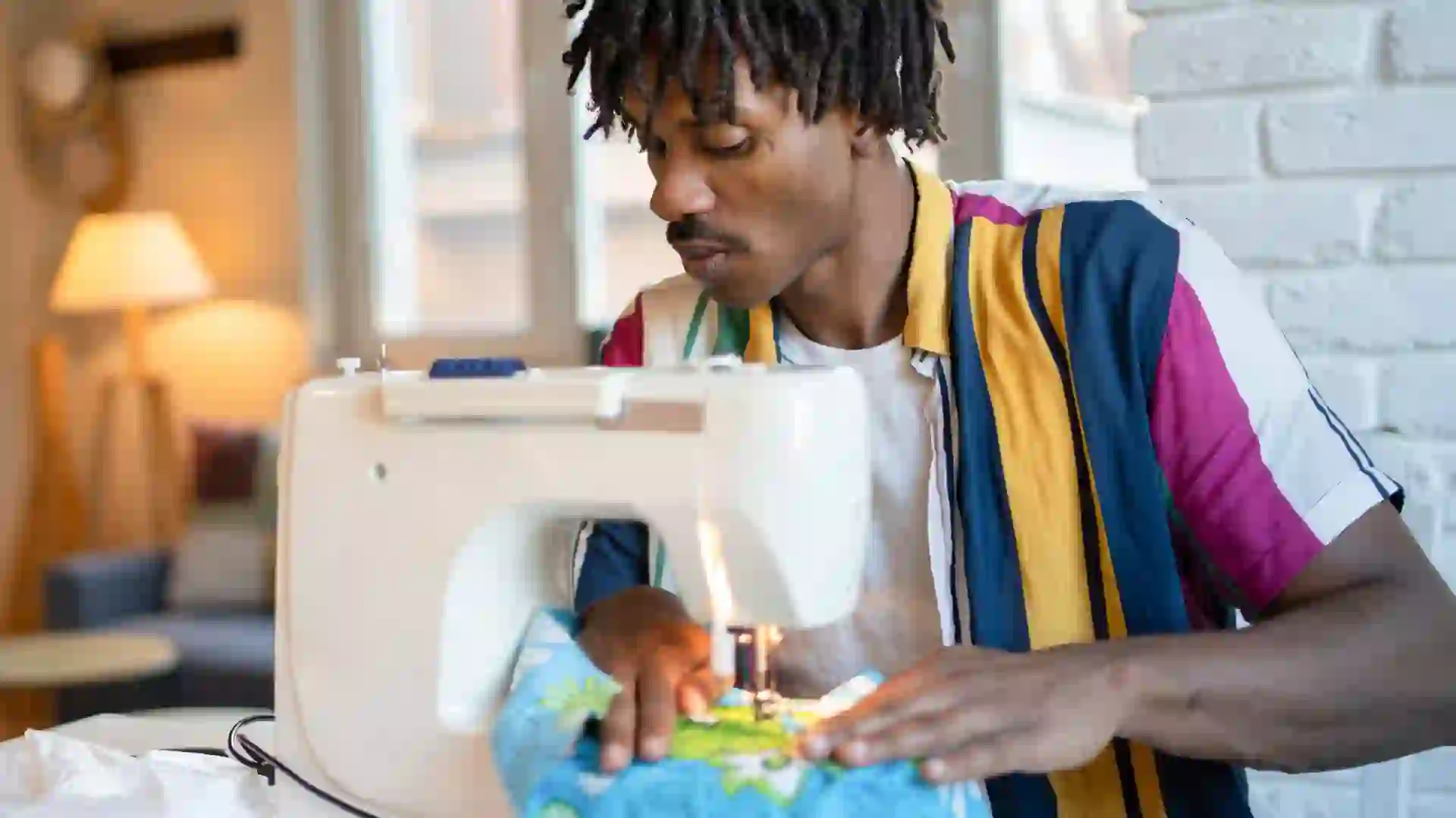 Man using sewing machine at home stock photo
