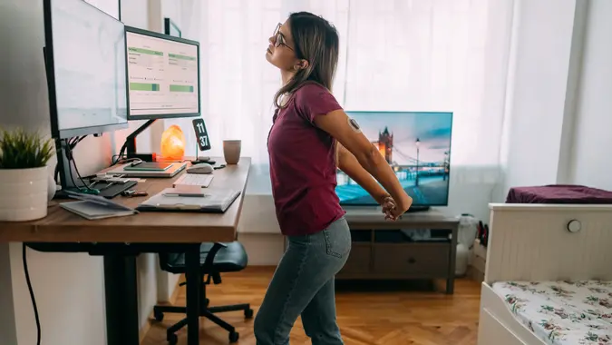 Woman at home office is walking on under desk treadmill stock photo