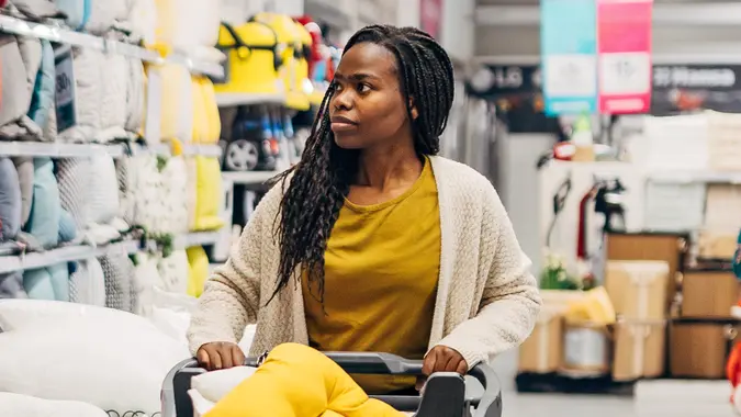 Black woman pushing a shopping cart in a department store.