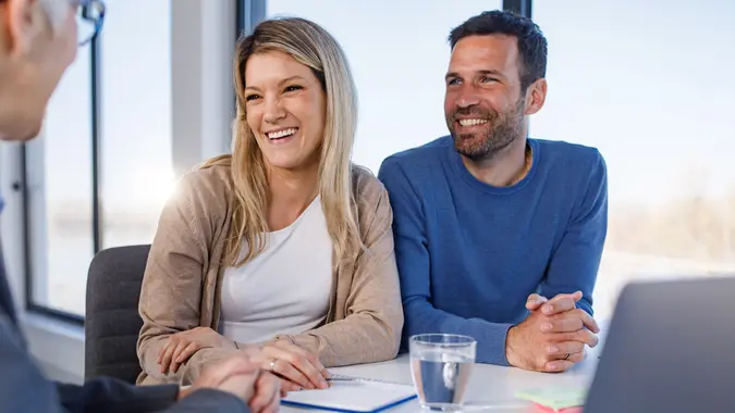 Happy couple talking to their agent on a meeting in the office. stock photo