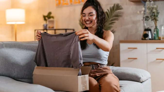 Young Woman Unboxing A Package With A New Shirt stock photo