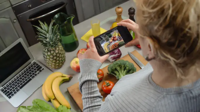 Picture of a mom taking a photo of food with focus on smartphone.