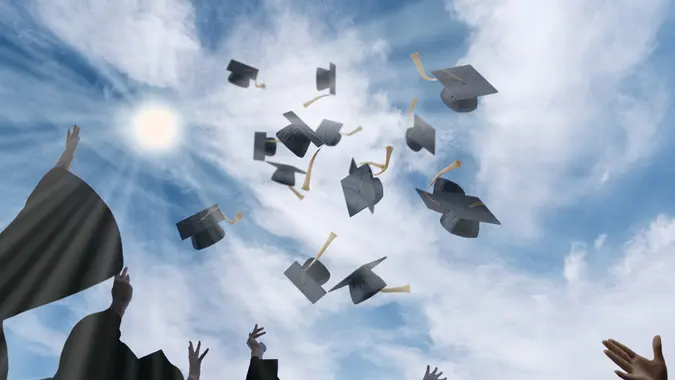 Graduating Students Throwing Graduation Caps in the Air Against Blue Sky stock photo