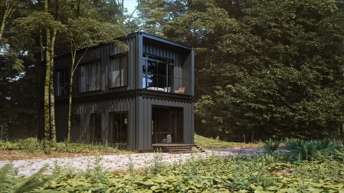 A minimalist black container house in a forest.