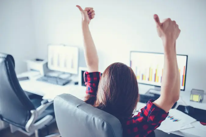 Portrait of happy young successful businesswoman celebrate something with arms up.