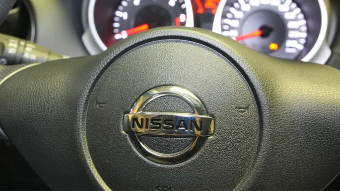 The Nissan brand logo on a steering wheel inside of a car, vehicle.