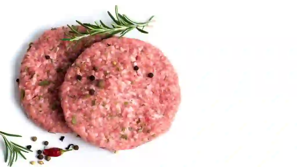 Two raw burgers with fresh spices on a white background isolated.