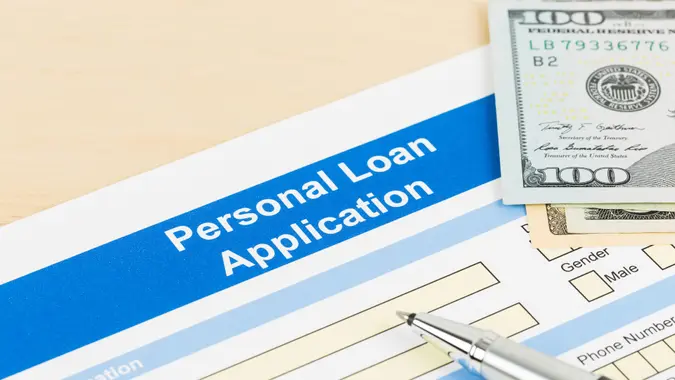 Personal loan application form with dollar money banknote, and pen.