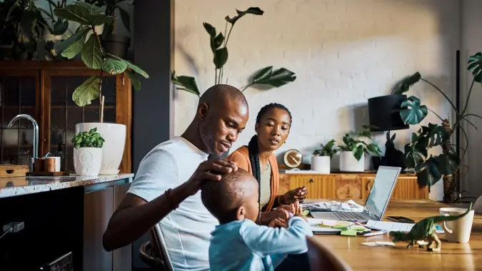 Family, children and budget with a couple using a laptop to invest or manage savings in the dining room of their home together.