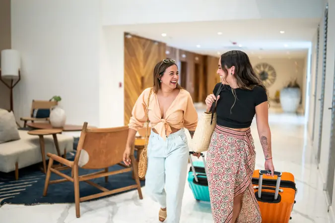 Traveler friends arriving at a hotel with their luggage.