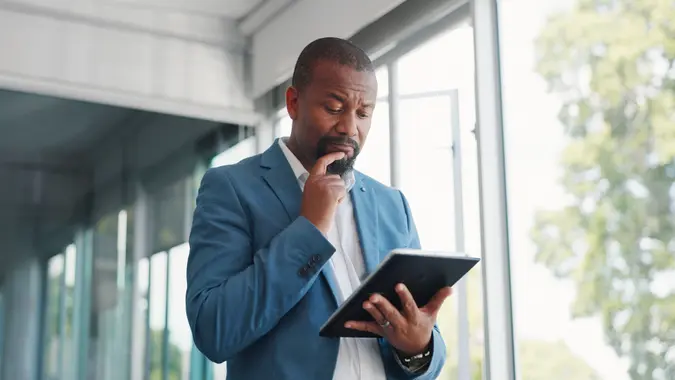Thinking businessman with tablet for corporate review and idea for finance, budget and stock market in office building.
