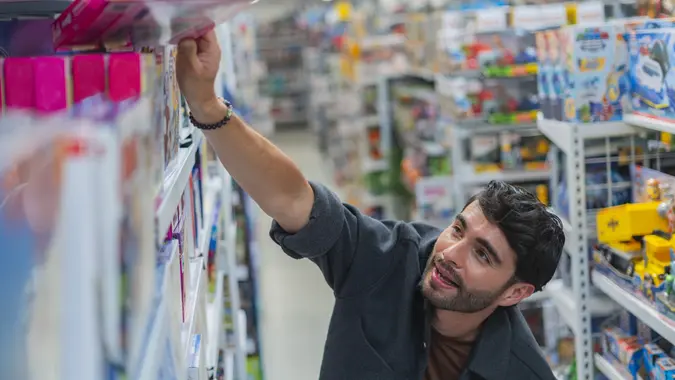Latino man is inside a chain store with his shopping cart looking for important items he needs for the house stock photo