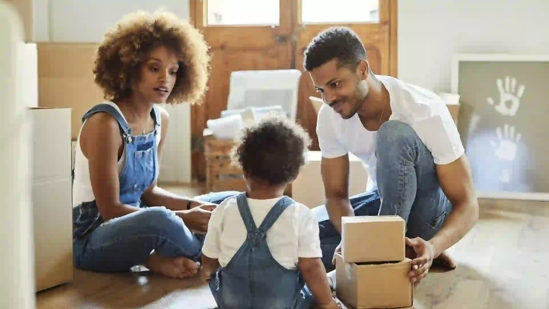 Family of three with cardboard boxes in new house stock photo