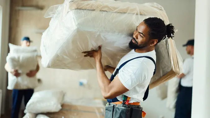 Young black mover carrying furniture in a new apartment. stock photo