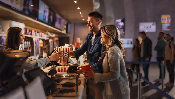 Happy couple buying popcorn and drinks in cinema. stock photo