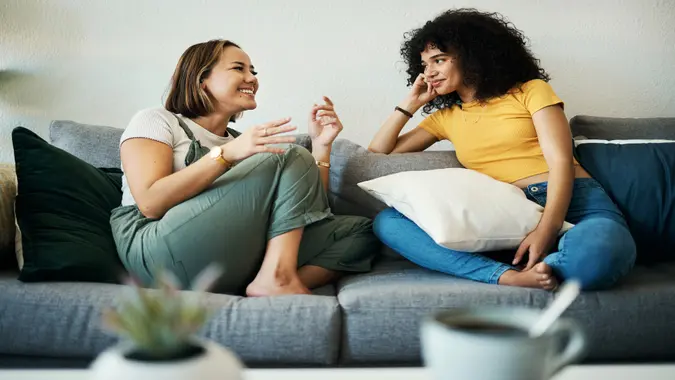 Women, friends talk and conversation in a home with gossip, discussion and happy in a living room.