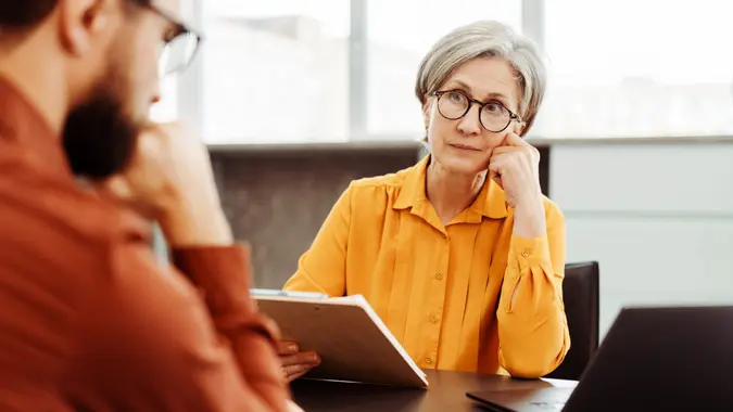 Serious senior woman, psychologist listening patient, looking for solution in modern office.