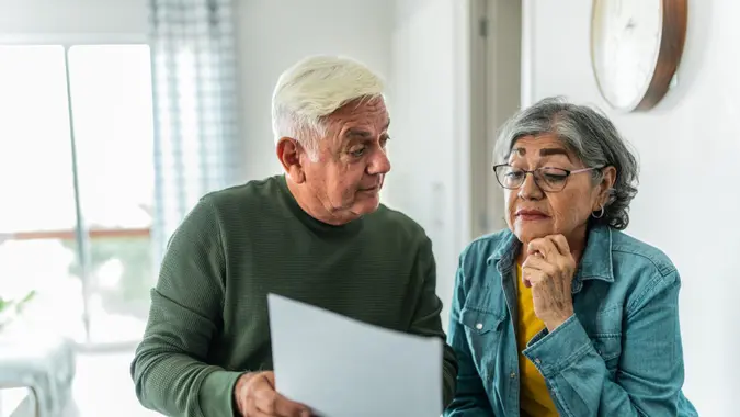 Senior couple using computer and doing home finances at home.